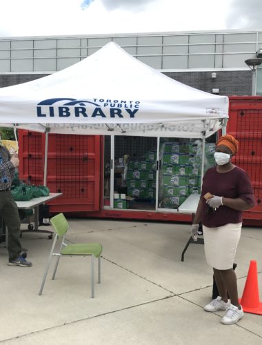 Toronto Public Library tent open in front of shipping container filled with food donations