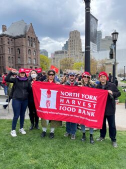 Six NYH staff holding the NYH banner in front of Queen's Park.