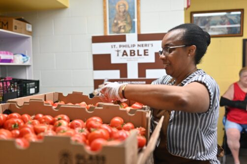 A woman sorts tomatoes for distribution at a food bank.