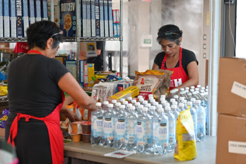 A person works in front of a mirror, loading food onto a table at the North York Harvest Food Bank.