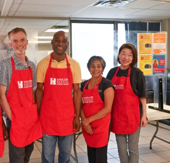 Four people wearing North York Harvest Food Bank aprons stand together for a group picture.