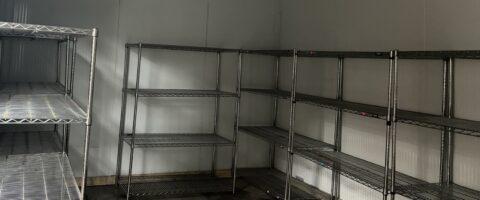 Empty shelves can be seen inside of a walk-in freezer.