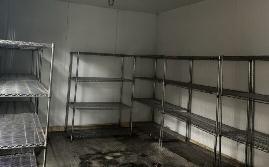 Empty shelves can be seen inside of a walk-in freezer.