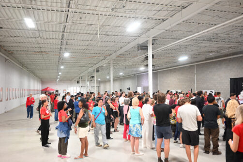 A crowd of people mingle in a large warehouse during an event at North York Harvest Food Bank.