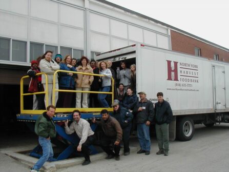 A group of people pose for a photo next to a red North York Harvest Food Bank truck.
