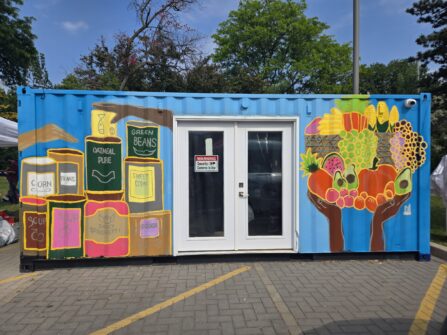 A shipping container is painted with illustrations of various canned goods.