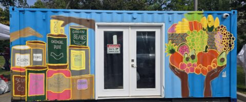 A shipping container is painted with illustrations of various canned goods.