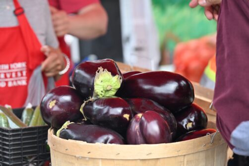 A basket of eggplant is on display at an outdoor market.