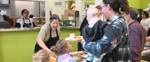 A mother and her three children are served food at a drop-in meal program supported by FoodReach.
