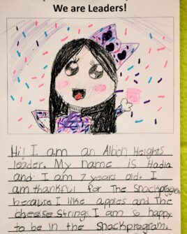 A child's drawing of herself with the title 'We Are Leaders' where a young girl describes that she is a leader because she is kind, and she loves the school snack program.