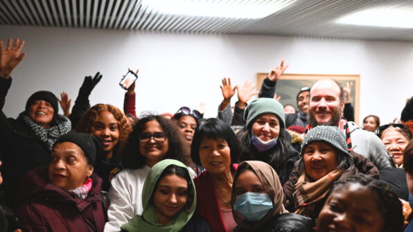 A group of people, some with their hands in the air, smile for a group shot at City Hall with Toronto Mayor Olivia Chow.