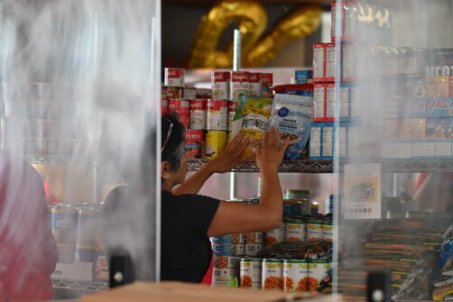 A person is visible through a plastic barrier stocking shelves at North York Harvest Food Bank.