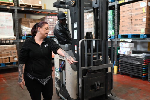 A woman instructs a person on a forklift during North York Harvest Food Bank's workforce training program at their warehouse in North York.
