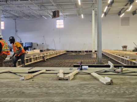 Construction workers are seen in a large industrial space, a hole in the floor is where a 5,000 sq. ft. refrigerated space will go.